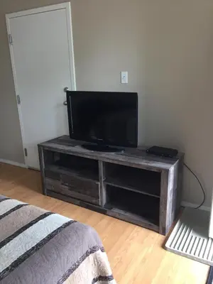 a flat screen tv on a wooden stand in a room at Kacee's Northern Suites in Fort Nelson