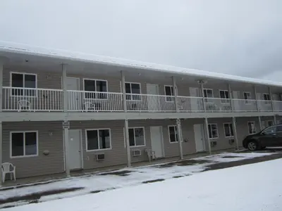 a building with balconies and a car parked in front at Kacee's Northern Suites in Fort Nelson
