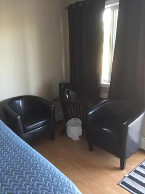 a bedroom with two black chairs and a bed at Kacee's Northern Suites in Fort Nelson