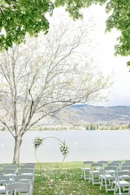 a row of white chairs sitting next to a lake at Watermark Beach Resort in Osoyoos