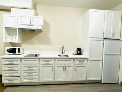 a kitchen with white cabinets and a white refrigerator at Southfort Inn in Fort Saskatchewan