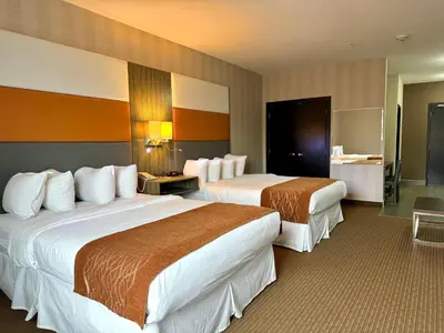 a hotel room with two beds and a bathroom at Southfort Inn in Fort Saskatchewan