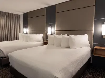 two beds in a hotel room with white pillows at Carriage House Hotel and Conference Centre in Calgary