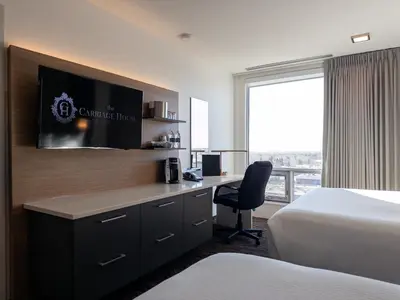 a hotel room with a bed and a desk with a television at Carriage House Hotel and Conference Centre in Calgary