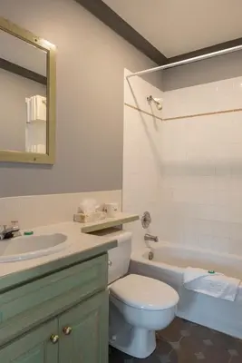 a bathroom with a toilet and a sink and a tub at Tiki Shores Inn & Suites in Penticton