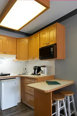 a kitchen with wooden cabinets and a counter with stools at Tiki Shores Inn & Suites in Penticton
