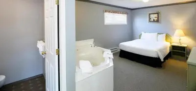 a bathroom with a bed and a tub in a room at Tiki Shores Inn & Suites in Penticton