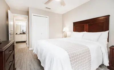 a bedroom with a large white bed with a wooden headboard at Canterra Suites Hotel in Edmonton