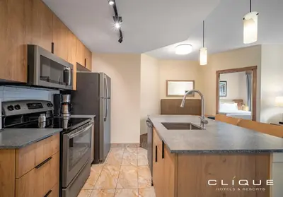 a kitchen with stainless steel appliances and wooden cabinets at Falcon Crest Lodge by CLIQUE in Canmore