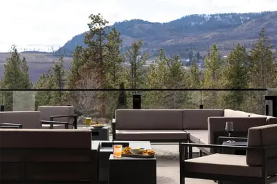a patio with couches and tables and a view of mountains at Doubletree By Hilton West Kelowna in West Kelowna