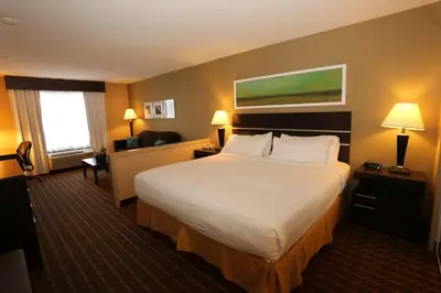 a hotel room with a large bed with white sheets at Holiday Inn Express Hotel & Suites Vernon by IHG in Vernon