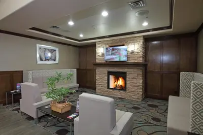 a living room with a fireplace and a table and chairs at Holiday Inn Express Hotel & Suites Vernon by IHG in Vernon
