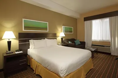 a hotel room with a large bed and a chair at Holiday Inn Express Hotel & Suites Vernon by IHG in Vernon