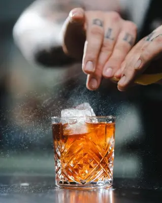 a person with tattoos on their hands and a glass of whiskey at Paradox Vancouver in Vancouver