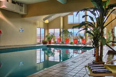 a swimming pool in a building with chairs and a plant at Holiday Inn Hotel & Suites Osoyoos by IHG in Osoyoos