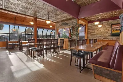 a restaurant with wooden tables and chairs and windows at Guest House Inn & Suites in Edson