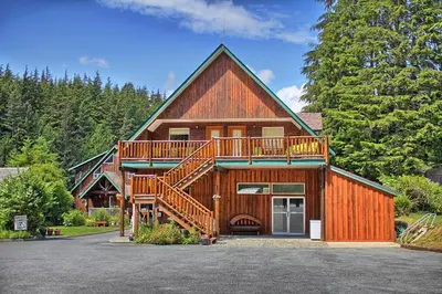 a large wooden house with a large deck at Wild Coast Wilderness Resort in Port Renfrew