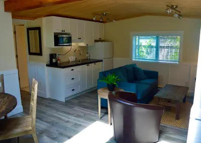 a living room with a blue couch and a kitchen at Wild Coast Wilderness Resort in Port Renfrew