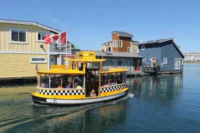 a yellow boat in the water next to buildings at A Float Home B&B in Fisherman’s Wharf in Victoria