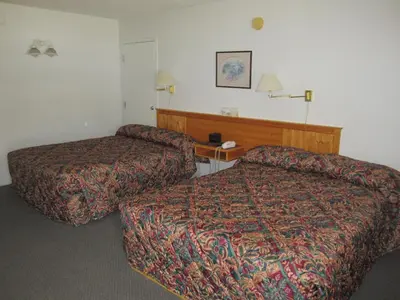 a hotel room with two beds and a desk at Bonanza Gold Motel & RV Park in Dawson City
