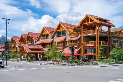 a large wooden building with red roofs on a street at Moose Hotel and Suites in Banff