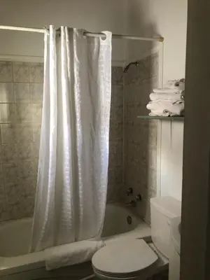 a bathroom with a white shower curtain and a toilet at Superlodge Lloydminster in Lloydminster