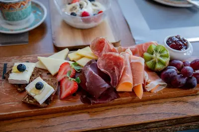 a plate of cheese and fruit on a cutting board at Beaujolais Boutique B&B at Thea's House- Adults Only in Banff