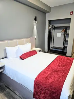 a bedroom with a large white bed with a red blanket at Ramada by Wyndham West Edmonton Hotel & Suites in Edmonton