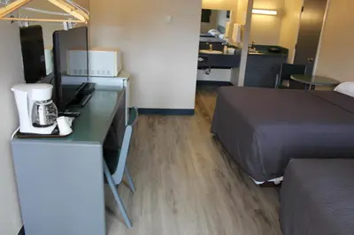 a hotel room with a bed and a desk with a laptop at Plains Motor Inn in Stettler