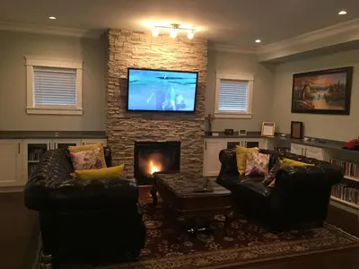 a living room with two leather couches and a fireplace at Vancouver Austin Guesthouse in Coquitlam