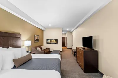 a hotel room with two beds and a flat screen tv at Best Western Plus Lacombe Inn and Suites in Lacombe