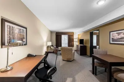 a hotel room with a desk and a living room at Best Western Plus Lacombe Inn and Suites in Lacombe