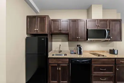 a kitchen with wooden cabinets and a black refrigerator at Best Western Plus Lacombe Inn and Suites in Lacombe