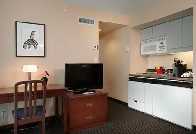 a kitchen with a desk and a tv in a room at Rosedale on Robson Suite Hotel in Vancouver
