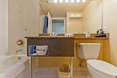 a bathroom with a toilet and a sink and a tub at Rosedale on Robson Suite Hotel in Vancouver