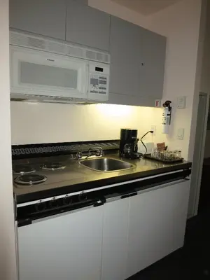 a kitchen with a sink and a microwave at Rosedale on Robson Suite Hotel in Vancouver