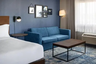 a hotel room with a blue couch and a bed at Four Points by Sheraton Edmonton South in Edmonton