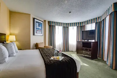 a hotel room with a bed and a flat screen tv at Sawridge Inn and Conference Centre Edmonton South in Edmonton