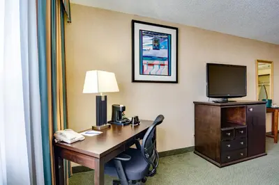a hotel room with a desk with a computer and a television at Sawridge Inn and Conference Centre Edmonton South in Edmonton