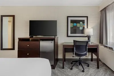 a hotel room with a desk with a television and a bed at Best Western Cedar Park Inn in Edmonton