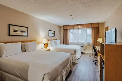 a hotel room with two beds and a flat screen tv at SureStay Plus by Best Western Coquitlam in Coquitlam