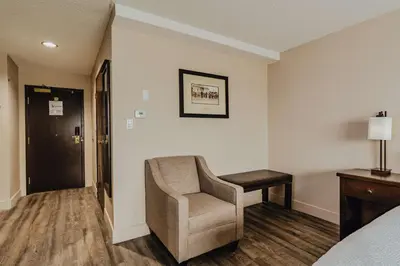 a hotel room with a chair and a bed at SureStay Plus by Best Western Coquitlam in Coquitlam
