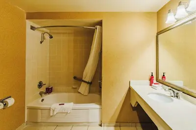 a bathroom with a tub and a sink at SureStay Plus by Best Western Coquitlam in Coquitlam