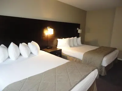 a hotel room with two beds with white pillows at Super 8 by Wyndham West Kelowna BC in West Kelowna