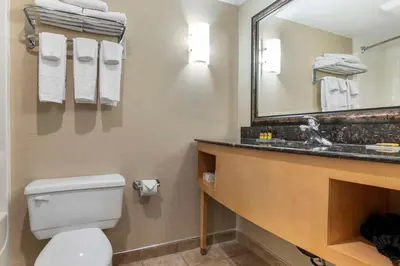 a bathroom with a toilet and a sink and a mirror at Best Western Plus Kelowna Hotel & Suites in Kelowna