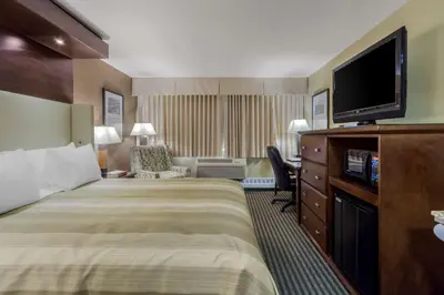 a hotel room with a bed and a flat screen tv at Best Western Premier Denham Inn & Suites in Leduc