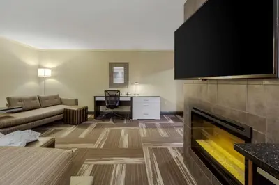 a living room with a couch and a fireplace at Best Western Premier Denham Inn & Suites in Leduc