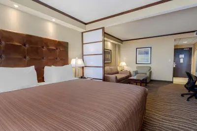 a hotel room with a large bed and a chair at Best Western Premier Denham Inn & Suites in Leduc