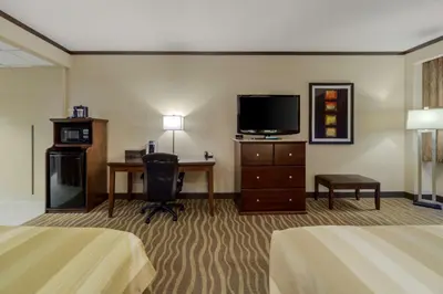 a hotel room with two beds and a flat screen tv at Best Western Premier Denham Inn & Suites in Leduc