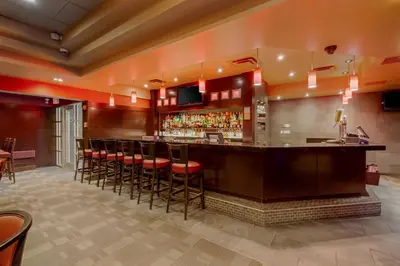 a bar in a restaurant with red walls and stools at Best Western Premier Denham Inn & Suites in Leduc
